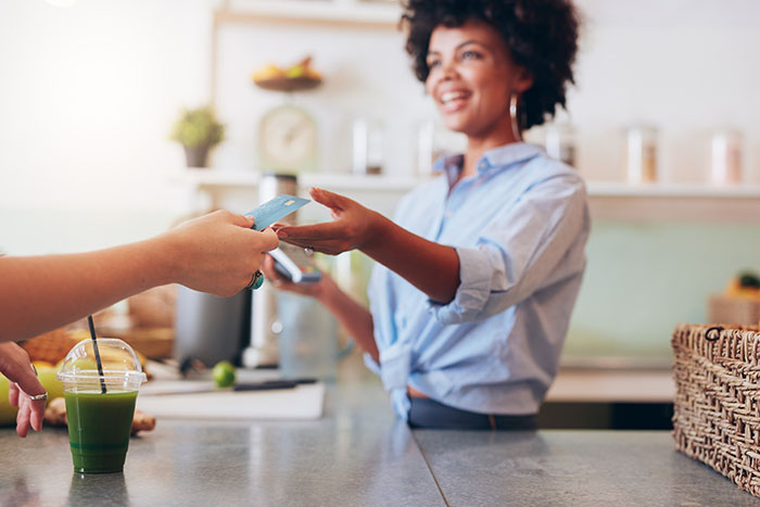 Female employee taking payment from customer Cropped shot of female employee taking payment from customer, focus on female hands giving credit card for juice bar payment.
